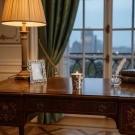 Bougie Porcelaine luxe blanc et or allumée, sur bureau bois ancien