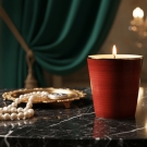 Pot à bougie Brun Rouge posé avec accessoires luxe, perles et plateau or