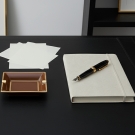 Cendrier Byzance caramel, posé sur un bureau élégant avec carnet et stylo plume noir et or.