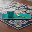 Tasse à café, Café des Délices turquoise et or, posée sur un tissu bleu à motifs