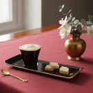 Tasse à café Café des Délices noir et or servie avec chocolats blancs sur nappe bordeaux