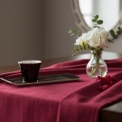 Tasse à café Café des Délices noir et or sur nappe bordeaux et bouquet de fleurs blanches