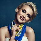 Portrait studio d’une femme souriante portant le carré de soie Anissa bleu et jaune Lorenza Di Filippo noué autour du cou.